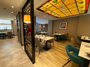 een restaurant met tafels en stoelen en een glas-in-loodplafond bij Hotel Lyskirchen in Keulen