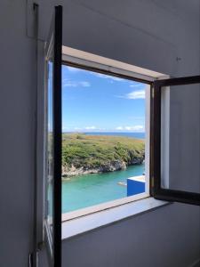 uma janela com vista para uma massa de água em Porto Covo Bay House em Porto Covo