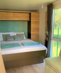 Camp Vransko lake - Mobile homes في باكوشتاني: غرفة نوم بسرير كبير مع اللوح الخشبي