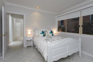 a white bedroom with a white bed and a window at Rawson's Retreat - Five Bedroom Home - Walk CBD - Includes Breakfast in Tamworth