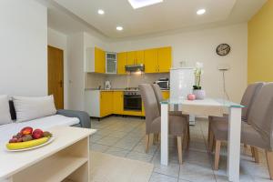 a living room and kitchen with yellow cabinets and a table at Apartments La Natalli in Baška