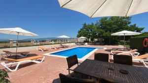 a swimming pool with chairs and umbrellas and a table and a pool at Turisme rural Can Genis in Peralada