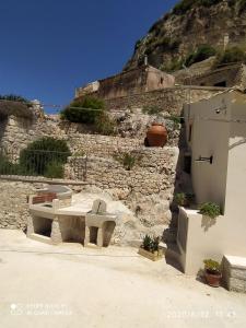 un edificio de piedra con un banco y una pared de piedra en La grotta di nonna minicchia n 49, en Scicli
