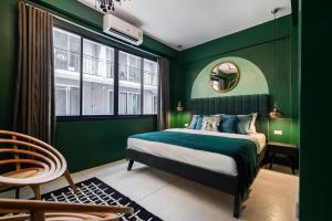 a green bedroom with a bed and a mirror at The Mellow at Silom in Bangkok
