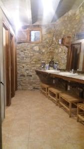 Baño de piedra con 2 lavabos y pared de piedra en Albergue Casa Fumenal, en Padarniu