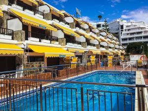 a swimming pool in front of a hotel at Apartamentos Sirena in Mogán