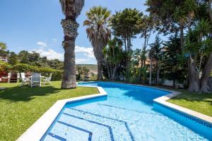 a swimming pool in a yard with palm trees at RENT4REST Sesimbra 4Bdr Ocean View and Private Pool Villa in Sesimbra