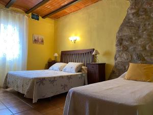 1 dormitorio con 2 camas y pared de piedra en Turisme rural Can Genis, en Peralada