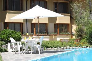 a white umbrella and chairs next to a swimming pool at Hosteria Las Lengas in San Martín de los Andes