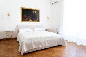 una camera bianca con un letto e un dipinto sul muro di Casa Vacanze Il Duomo a Catania