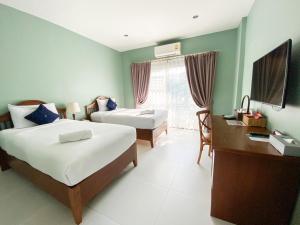 Habitación de hotel con 2 camas, escritorio y escritorio. en Koranaree Courtyard Boutique Hotel en Nakhon Ratchasima