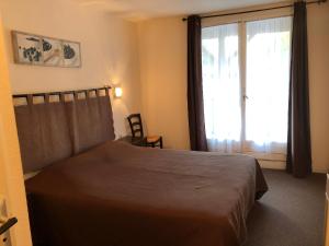 a bedroom with a bed and a large window at Hôtel Restaurant Les Falaises in Bouziès