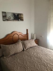 łóżko z drewnianym zagłówkiem w sypialni w obiekcie apto Fradera w mieście La Savina