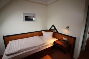 a small bedroom with a bed and a night stand at Hotel Reke in Plau am See