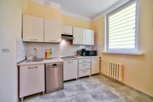 a small kitchen with white cabinets and a window at Apartament u Ewy w Kołobrzegu - Podczele in Kołobrzeg