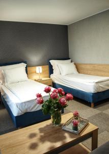 una camera d'albergo con due letti e un tavolo con fiori di Hotel Rudnik a Grudziądz