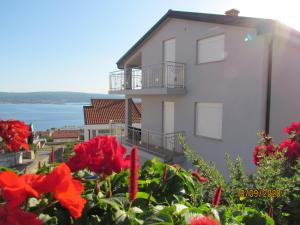 a white building with red flowers in front of it at Apartment Delic in Crikvenica