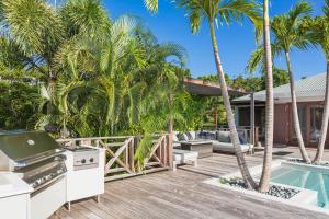 a backyard with a grill and a swimming pool with palm trees at Dream Villa Gouverneur 655 in Saint Barthelemy