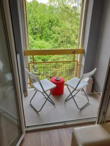 duas cadeiras e um vaso vermelho sentado numa varanda em Apartman 4 - Studio Janja em Sokobanja