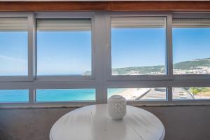 セジンブラにあるRent4rest - Sesimbra Ocean View Studioの白いテーブル(窓の前に花瓶付)