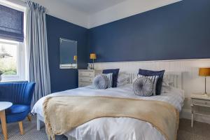a blue bedroom with a large bed with blue walls at Blakeney House in Blakeney