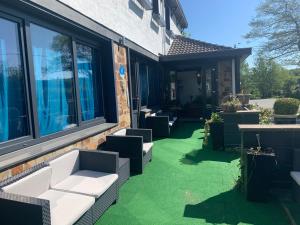 een patio met witte meubels en groen gras bij Hotel Le Montana in Werbomont