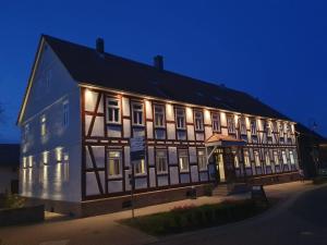 Un grand bâtiment est éclairé la nuit. dans l'établissement Landgasthof-Hotel Zur Linde, à Großenlüder