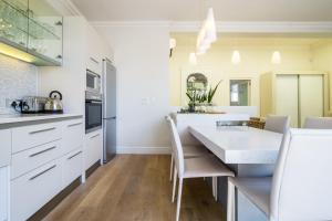 a kitchen with white cabinets and a table and chairs at Tuishuisie in Stellenbosch
