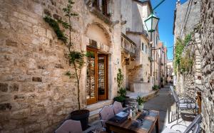 eine Gasse mit Tischen und Stühlen in einem alten Gebäude in der Unterkunft Luxury Apartment Bifora in Hvar