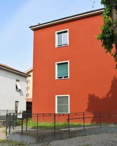 un edificio rojo con dos ventanas y una valla en Ostello di Saronno - Malpensa Hostel, en Saronno