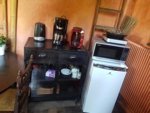 a microwave on top of a refrigerator next to a table at En pleine nature in Bonneuil-en-Valois