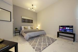 a bedroom with a bed and a flat screen tv at SHH - Furnished Studio in Dubai South Near to Expo 2021 in Dubai