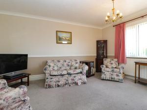 a living room with two chairs and a flat screen tv at Hill View in Swanage