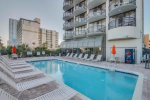 ein Swimmingpool mit Stühlen und einem Gebäude in der Unterkunft Hosteeva 1-bedroom Meridian Plaza Condo with Ocean View in Myrtle Beach