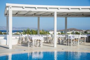 a patio with white chairs and a swimming pool at Cycladic Islands Hotel & Spa in Agia Anna Naxos