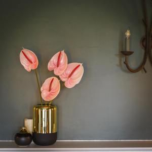 two pink flowers in a gold vase on a table at Blakeney House in Blakeney