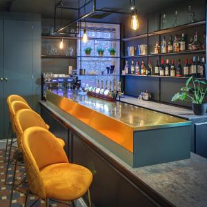 a bar with orange chairs and bottles of alcohol at Blakeney House in Blakeney