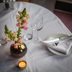 a table with a vase with flowers and a candle at Blakeney House in Blakeney