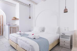 a white bedroom with two beds with towels at Cycladic Islands Hotel & Spa in Agia Anna Naxos