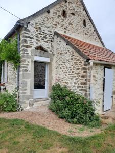 una vieja casa de piedra con una puerta blanca en Le Gîte De L'Ouche Charlot, en Maux