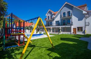 a yard with a playground in front of a house at Rewit Dom Goscinny z podgrzewanym basenem in Rewal