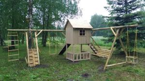 a wooden playground with a slide and a play house at Guest house LAUKMALI in (( Falcgrāve ))