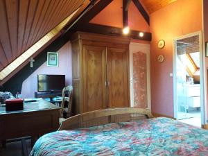 um quarto com uma cama, uma secretária e uma televisão em La Petite Londe em Biéville-Beuville