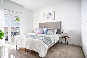 Dormitorio blanco con cama grande con almohadas azules y rosas en Sia Mare City Center Apartment, Rhodes en Rodas
