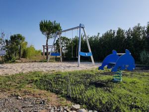 an empty playground with a swing and a swing at Camping Paradis 4 étoiles Au Port de L'Houmeau - La Rochelle in LʼHoumeau