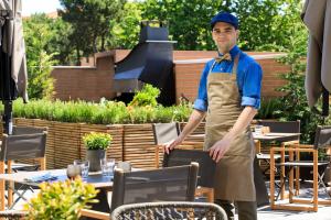 a man in an apron standing in a garden at Almar Jesolo Resort & Spa in Lido di Jesolo