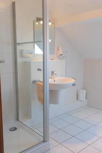 a bathroom with a glass shower and a sink at Gasthaus Jütte in Ebergötzen