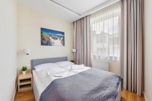a bedroom with a large bed and a large window at Apartamenty Sun & Snow Marina Kąty Rybackie in Kąty Rybackie