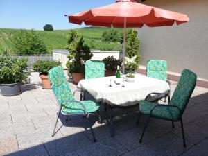 a table and chairs with an umbrella on a patio at Wein-und Gästehaus Alfons Bollig in Trittenheim