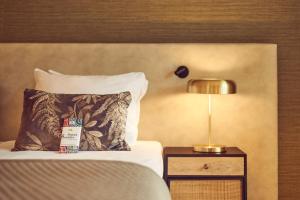 a bed with a pillow and a lamp on a night stand at Van der Valk Hotel Arnhem in Arnhem